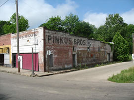 A brick building features faded signage for the Pinkus Bros. store.