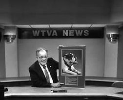 Jack Cristil holds a picture of a bulldog, the mascot of Mississippi State University, in the WTVA News studio.
