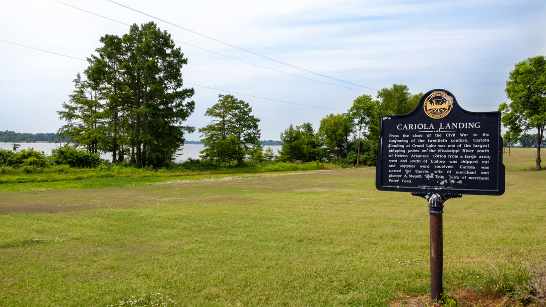 Grassy area with a historical marker for Cariola Landing in the foreground and Grand Lake in the background.