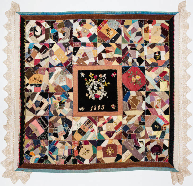 Nearly square quilt with lace trim. Thirty-two smaller squares surround a central square with the year 1885 embroidered on it. Small squares feature variety of asymmetrical designs sewn from multiple colors of scrap cloth. 