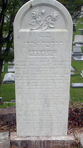 Headstone with roses and Hebrew lettering. The first two sections of text read, 