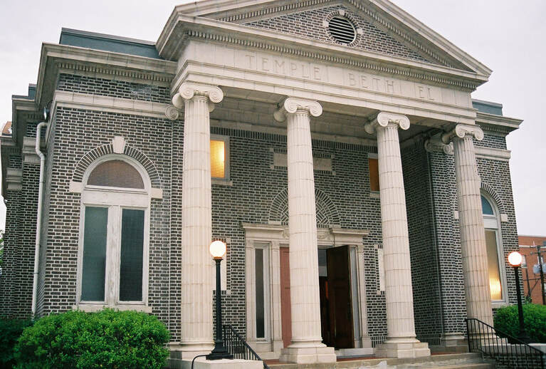 A brick, neoclassical synagogue, featuring four tall ionic columns at the entryway.