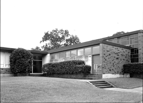 Black-and-white photo of a modest, mid-century brick synagogue with a flat roof.